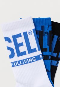 Tres pares de calcetines de tripulación: blancos con letras azules, azules con detalles en negro y negros con letras azules; textura acanalada en todo el calcetín.