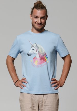 Lichtblauw shirt met korte mouwen met een eenhoorn afbeelding met een meerkleurige manen en sterren, tekst leest "FLASH DE EENHOORN." Zachte stof textuur.
