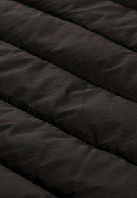 Schwarzer, gesteppter Stoff mit horizontaler Kanälen, der eine glatte, matte Textur und einheitliches Erscheinungsbild aufweist.