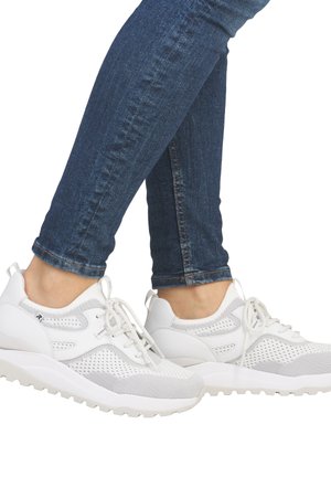 Weiße Sportlichkeitsschuhe mit einem Netzdesign, texturierten Akzenten und einer dicken, weißen Sohle. Die Schnürsenkel sind ebenfalls weiß. Getragen mit blauen Jeans.