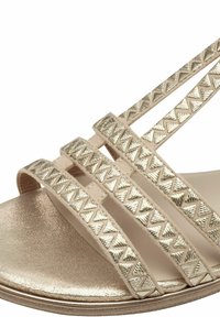 Metalinės auksinės spalvos sandalai su juostomis, turinčiomis geometriškai tekstūruotą raštą; minkštas padas su lygiu, blizgiu paviršiumi.