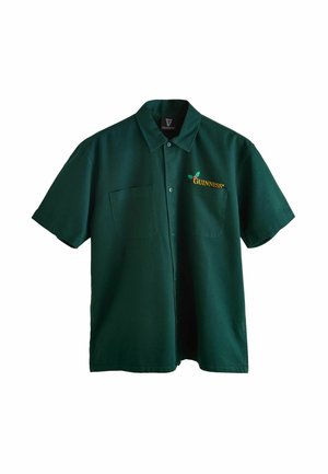 Groene korte mouwen shirt van stof met een kraag, voorzien van een gele geborduurde Guinness-logo en een zak aan de linkerkant.
