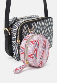 Crossbody bag with a geometric gray and black pattern; features gold hardware. Small round pouch in pink with a similar pattern and zipper.