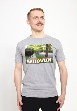 Graues T-Shirt mit einem Frontgrafik eines Straßenbildes mit Bäumen und dem Text "JOHN CARPENTER'S HALLOWEEN" in fetter, gelber Schrift.