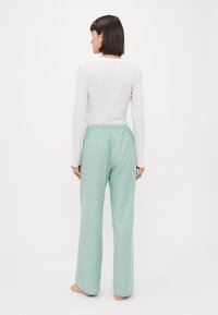 Top bianco a maniche lunghe leggero abbinato a pantaloni da pigiama a righe verde menta con vita elasticizzata e vestibilità ampia.