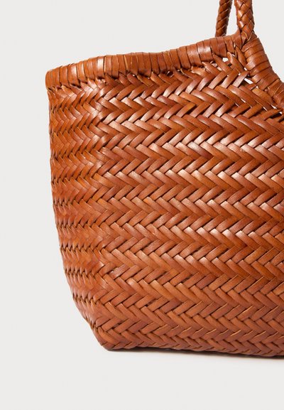 Καφέ πλεκτή δερμάτινη τσάντα tote με πλεχτό χερούλι, που διαθέτει σφιχτό σχέδιο ζιγκ-ζαγκ σε ανοιχτό φόντο.