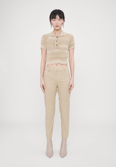 Beige strikket kort polo med korte ermer, tre-knappslukking; kombinert med lyse beige skrædderbukser og myke taupe ankelstøvler.