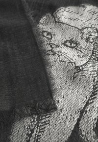Écharpe noire ornée d'un design texturé brodé d'un chat gris. Bords duveteux, détails complexes, mettant en valeur les traits et l'expression du chat.