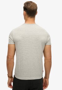 Grå kortærmet t-shirt lavet af tekstureret stof, med rund halsudskærmning og et lille mærketag ved kanten.
