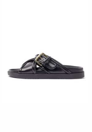 Sandale en cuir noir à enfiler avec une semelle épaisse, un design à sangle croisée et un accent de boucle dorée. Matériau texturé avec une finition lisse.