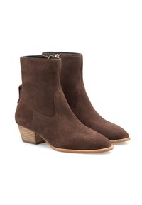 Bottines en daim marron avec un bout légèrement pointu, un talon en bois empilé et des coutures latérales. Elles sont dotées d'une fermeture éclair sur un côté et d'une languette de traction.