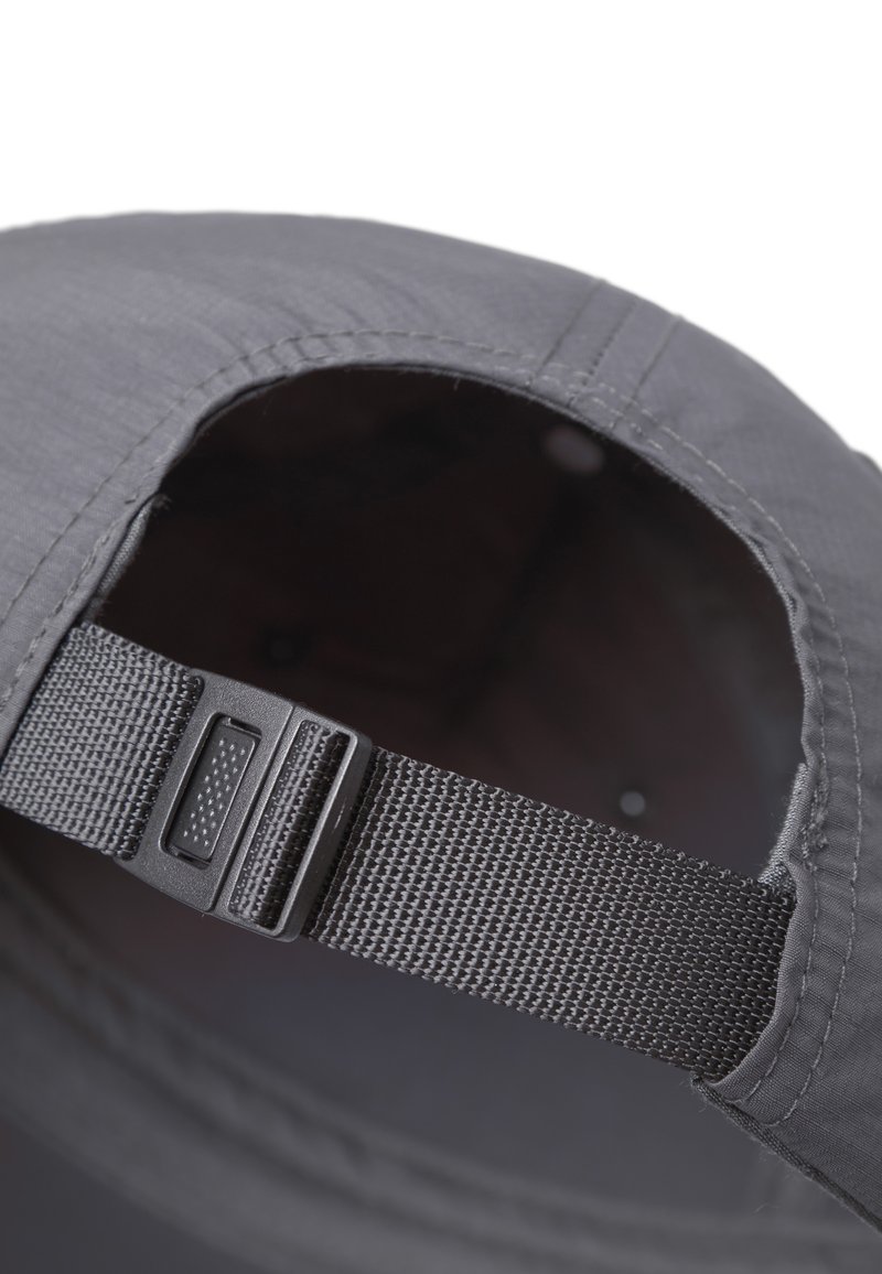 Primo piano di una cinghia nera regolabile con fibbia di plastica sul retro di un berretto di tessuto scuro.