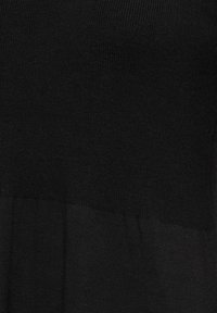 Tissu en tricot noir avec une texture subtile et une légère variation de ton de couleur dans les sections horizontales.