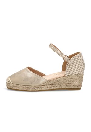 Alpargata cuña beige con puntera cerrada, correa ajustable en el tobillo y detalle tejido en el talón.