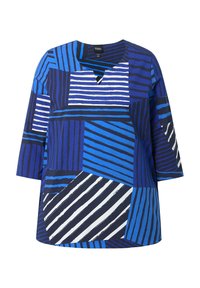 Blauwe top met patroon en V-hals, met verschillende tinten blauw, witte strepen en geometrische vormen. Korte mouwen en een losse pasvorm.