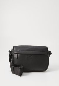 Borsa a tracolla in pelle nera con superficie testurizzata, dotata di chiusura con zip superiore e tracolla regolabile. Accento del logo sul davanti.