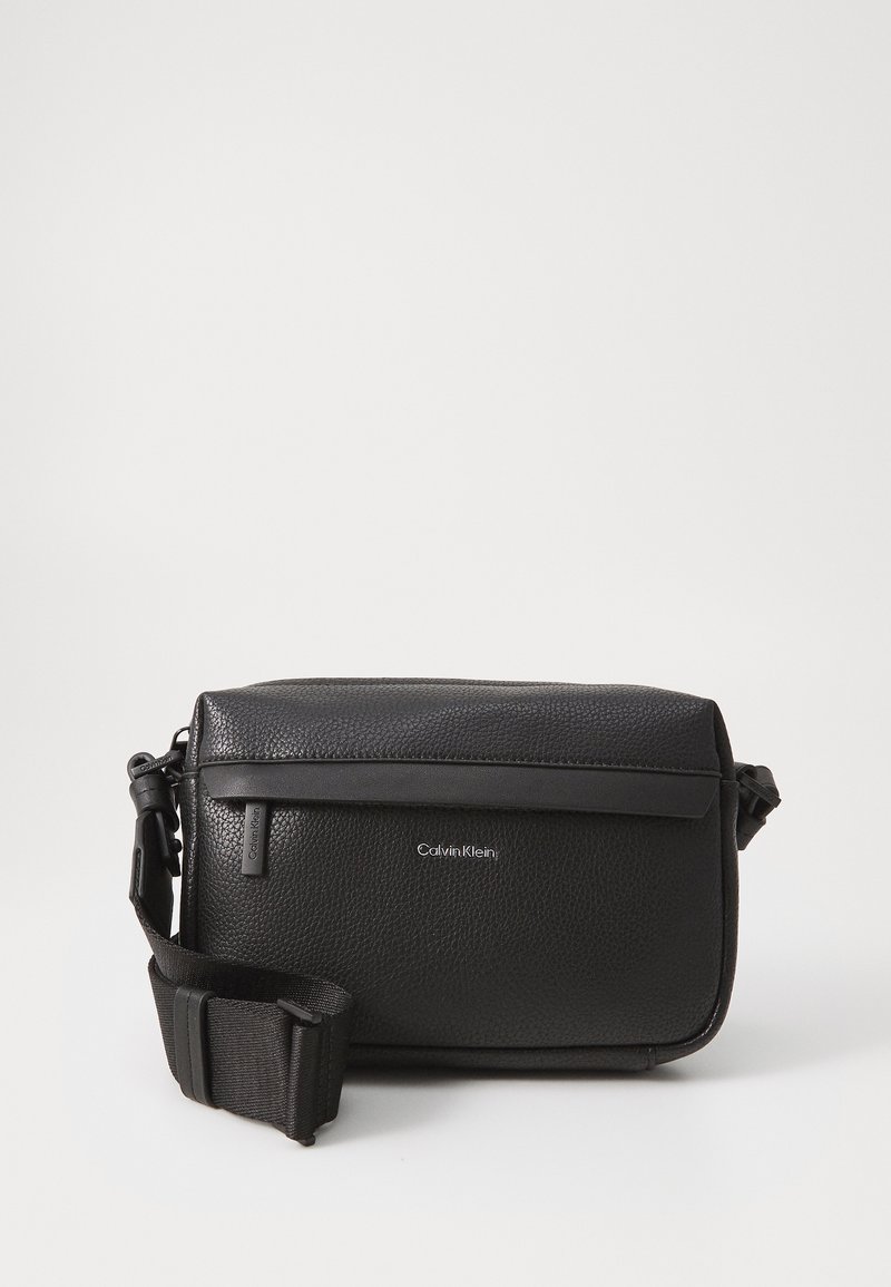 Borsa a tracolla in pelle nera con superficie testurizzata, dotata di chiusura con zip superiore e tracolla regolabile. Accento del logo sul davanti.