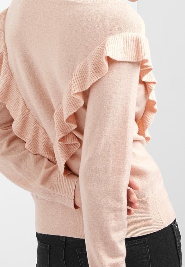 Hellrosa Pullover mit gerippter Struktur und einem Rüschendetail auf der Rückseite. Langer Ärmel, taillierte Passform und weiches Material.