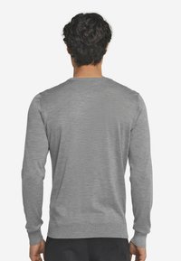 Grå stickad tröja med långa ärmar och en klassisk rund halsringning. Slät yta och ribbade cuffs och nederkant.