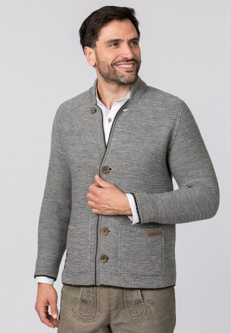 Grauer Strickcardigan mit Schalkragen, ausgestattet mit Holzknöpfen, zwei vorderen Taschen und einer strukturierten Oberfläche. Akzente sind der kontrastierende Besatz.