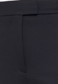 Marinblå skräddarsydda byxor i texturerat tyg, med platt frontficka och ren sömnad längs midjan.