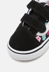 Dětská obuv z černé jemné kůže s květinovými vzory v růžové a tyrkysové, s bílými suchými zipy a texturovanou bílou gumovou podrážkou.