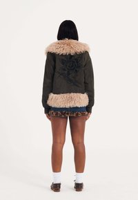 Olivově zelená bomber bunda s růžovým umělým kožešinovým límcem, s černou květinovou výšivkou na zádech a texturovaným lemem.