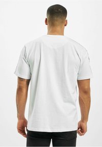 White cotton T-shirt with short sleeves, round neck, and a smooth texture. Features a plain back view, no visible patterns or logos.