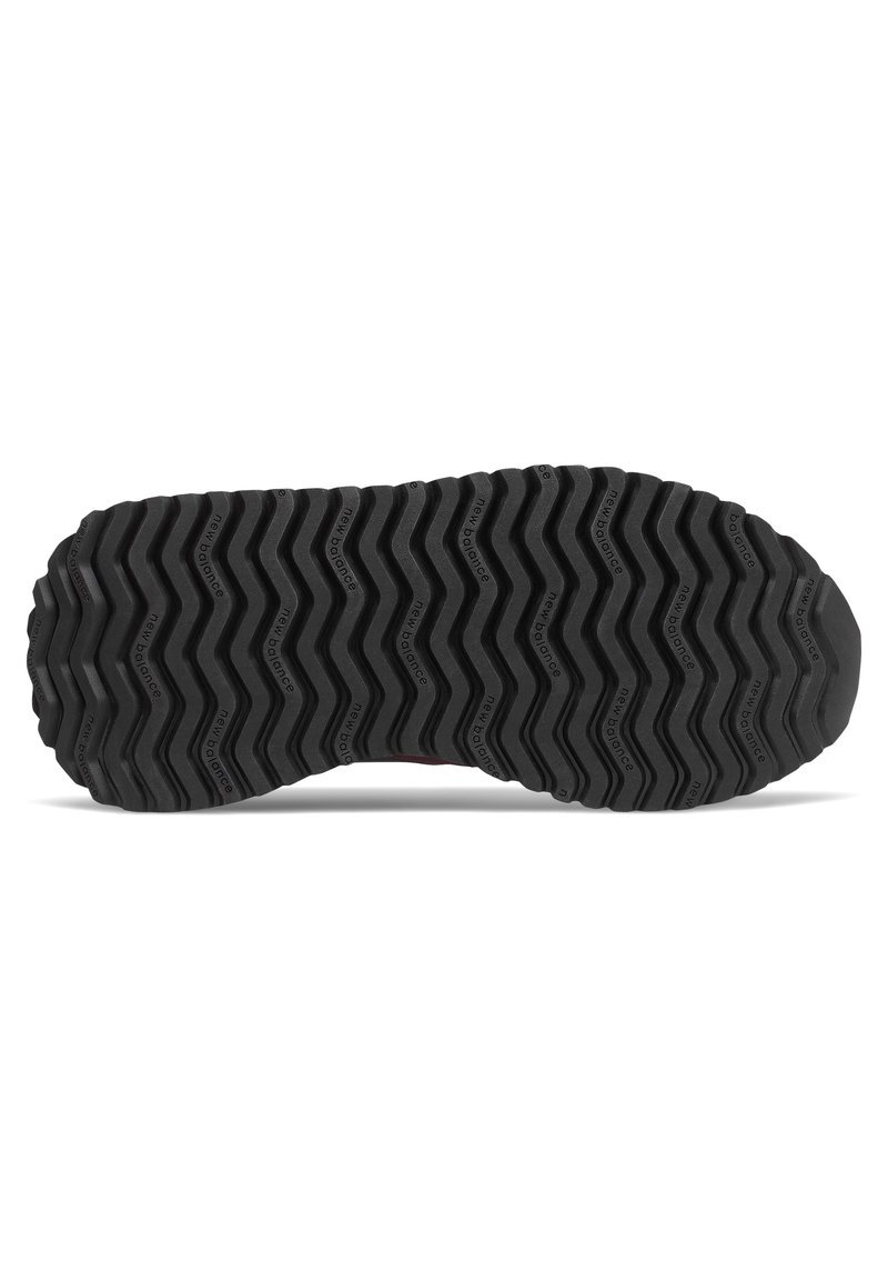 Suela de zapato de goma negra con patrón de banda de rodadura en zigzag y texto "new balance" repetido a lo largo de las ranuras.