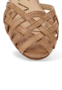 Sandalias tejidas marrones con un diseño entrelazado, acabado texturizado y puntera abierta, montadas sobre una suela plana.