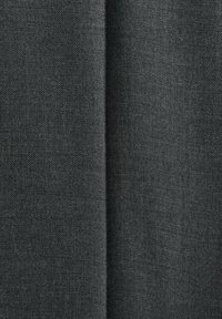 Gros plan sur un tissu noir avec une couture verticale visible au centre et une texture tissée fine.