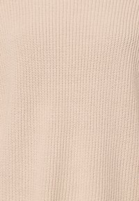 Suéter de punto en un suave beige. Presenta un tejido texturizado con un patrón de canalé, ofreciendo una apariencia suave y tejida con un corte relajado.