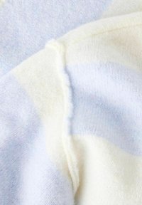 Gaiši zils un krēmkrāsas adīts audums ar mīkstu faktūru, ar horizontālām svītrām un nedaudz frēzētām malām.