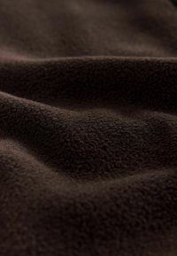 Brown fleece fabric showing a rich, soft texture with a wavy pattern, highlighting its plump, warm appearance.