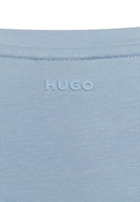 Lichtblauwe ribstof die een gestructureerd oppervlak toont, met een reliëf "HUGO" logo nabij de halslijn.