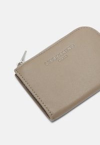 Beżowy skórzany portfel z teksturowaną powierzchnią, zamkiem błyskawicznym i tłoczonym logo marki na przodzie. Kompaktowy, prostokątny kształt.