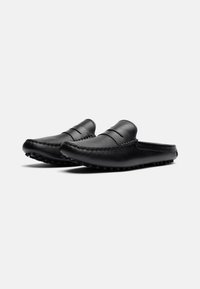 Schwarze Lederclogs mit glatter Oberfläche, ausgestattet mit gestickten Details und einer niedrigen, strukturierten Gummisohle für guten Halt. Abgerundete Zehenform.