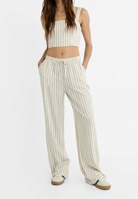 Ensemble deux pièces à rayures comprenant un débardeur court et un pantalon ample en beige et crème, confectionné dans un tissu doux et texturé.
