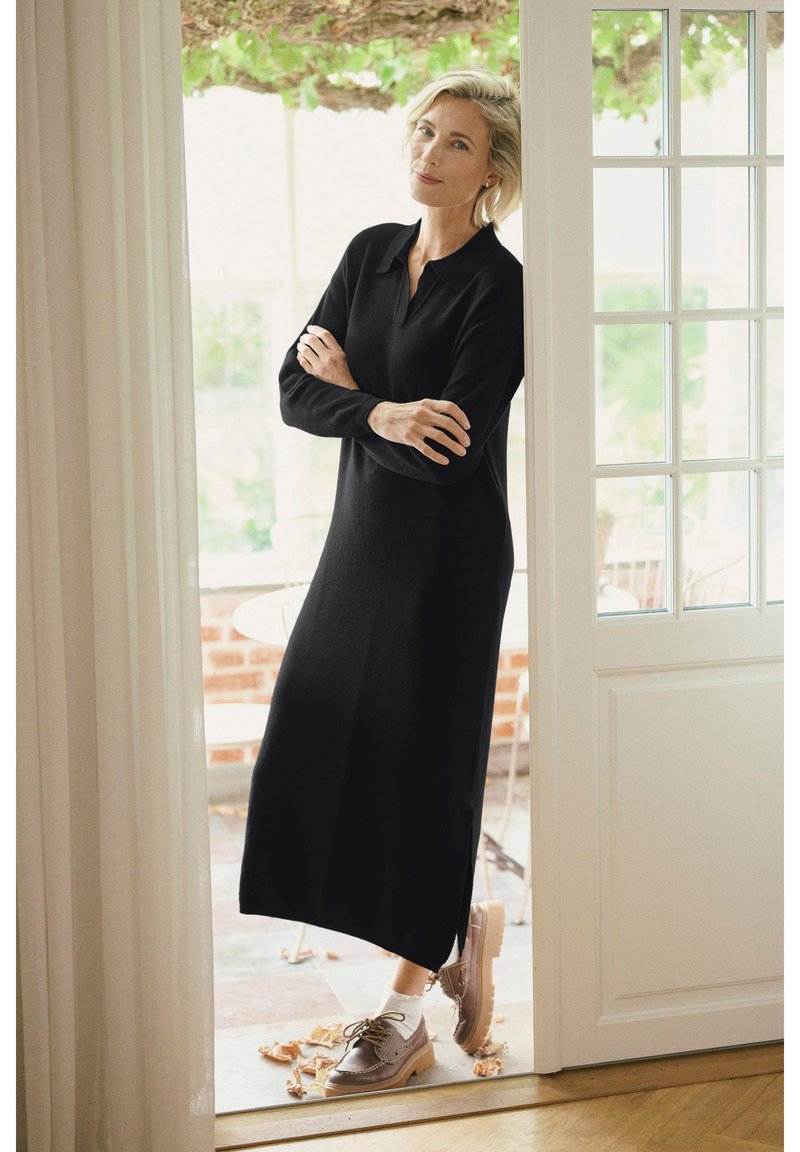 Black long-sleeve dress with a collared neckline, made of a soft material. Paired with light brown lace-up shoes and ankle socks.