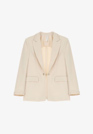 Blazer beige su misura con colletto, due tasche frontali e due bottoni metallici. Tessuto liscio con interno foderato.