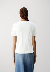 Bílá bavlněná trička s krátkými rukávy, klasickým výstřihem a volným střihem. Kombinováno se džínovou sukní, což vytváří pohodlný styl.