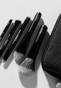 Set med KIKO Milan sminkborstar med svarta skaft. Borstarna har olika former på borsthuvudet och mjuka borststrån. Texturerat svart förvaringsfodral ingår.