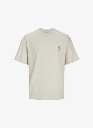 Camiseta de manga corta beige de algodón suave; presenta un pequeño estampado floral azul en el lado izquierdo del pecho; corte relajado con cuello redondo.