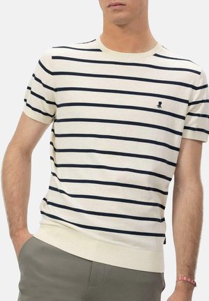 Suéter blanco de manga corta con rayas en azul marino, cuello redondo y dobladillo acanalado. Presenta un pequeño emblema en el pecho.