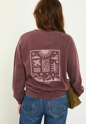 Purple oversized sweatshirt with a graphic print featuring mountains, trees, and clouds. Cozy fabric, ribbed cuffs, and casual fit.
