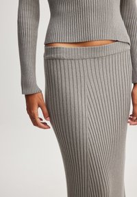 Completo a due pezzi in maglia a costine grigio chiaro, composto da un top corto e una gonna a vita alta con righe verticali e silhouette aderente.