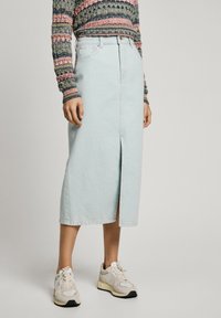 Lys blå denim midi skjørt med frontsplitt, høy midje og et rent design, kombinert med nøytrale sneakers.