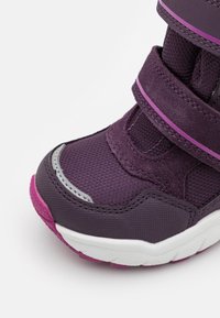 Lila Sportschuh aus Mesh- und Synthetikmaterial, mit zwei Klettverschlussriemen, silbernen Details und weißen sowie rosafarbenen Sohlenakzenten.