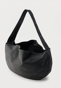 Fekete vászontáska vállra, laza kialakítással, tetején cipzáras záródással és sima, matt textúrával. Ívelt forma és hosszú pánt.