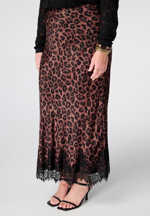 Rok met luipaardprint en zwarte kanten rand, gedragen met een zwart kanten top en zwarte sandaaltjes met bandjes, gecompleteerd met ringen en armbanden.